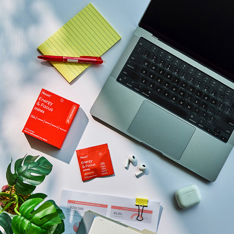 Neuro Energy & Focus Mints pack and sachet on a desk with laptop, earbuds and stationery
