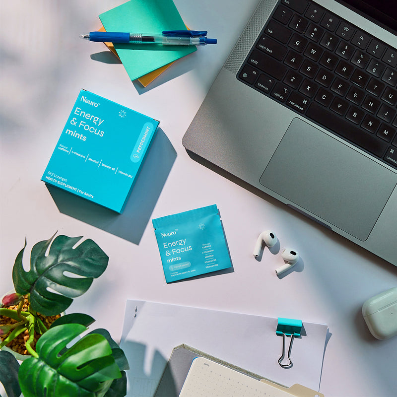 Neuro Energy & Focus Mints pack and sachet on a desk with laptop, earbuds and stationery